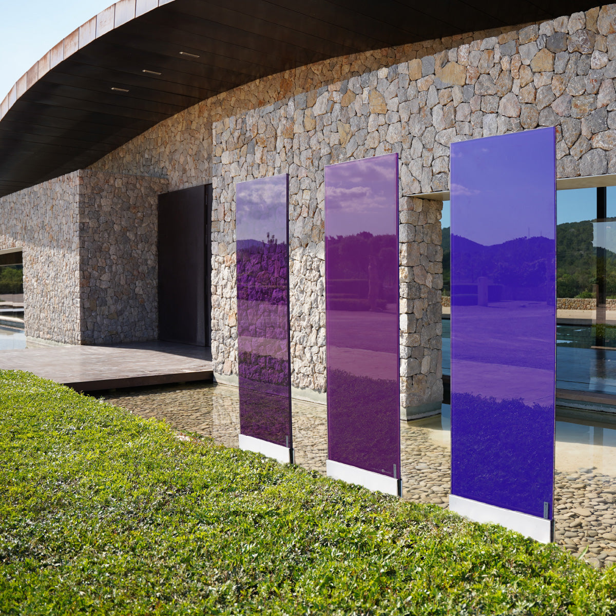 Die drei violetten Glasdesign Elemente stehen nebeneinander vor einem Weingut in Mallorca.